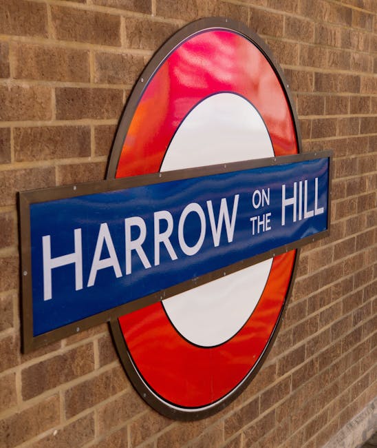 A close-up of a London Underground-style sign mounted on a brick wall, featuring a blue rectangular panel with white text reading 'HARROW ON THE HILL' aligned centrally across a circular background wi